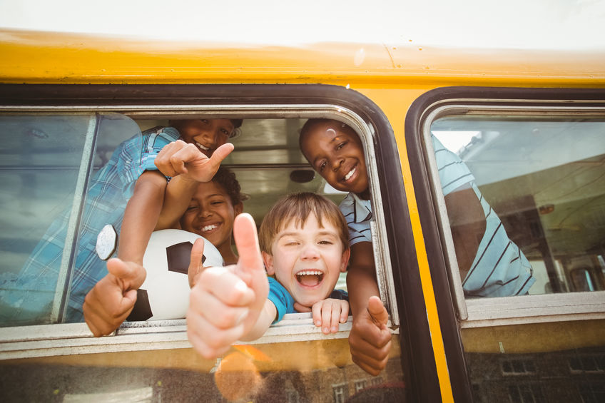 kids smiling and waving on school bus