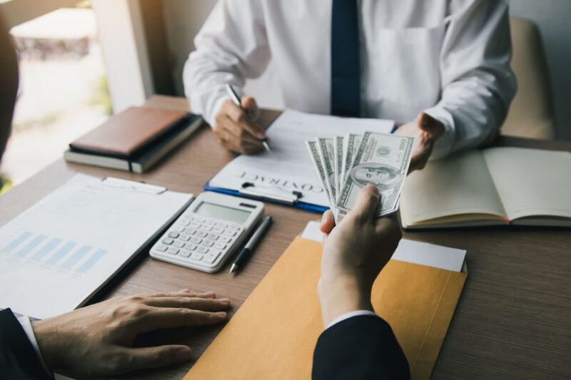 loan advisor and customer negotiating a loan agreement for a bus purchase. customer handing over cash down payment.